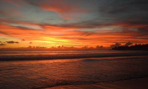 Scenic view of sea against dramatic sky during sunset