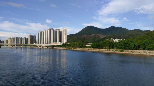 Scenic view of river by buildings against sky