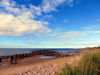 Scenic view of beach and sea against cloudy sky