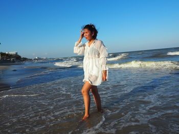 Full length of man standing on beach against clear sky