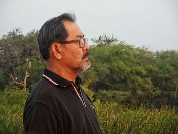 Portrait of mature man looking away on field against sky
