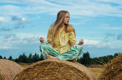 Full length of woman sitting on field against sky