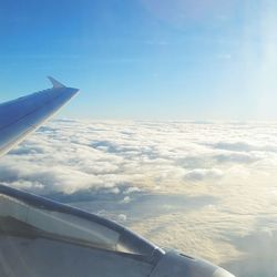 Airplane flying over landscape against blue sky