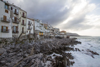 Buildings by sea against sky