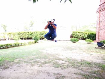 Young woman jumping in mid-air against clear sky