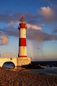 Lighthouse by sea against sky