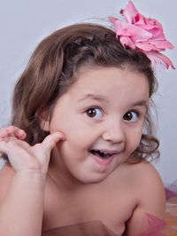 Portrait of cute girl with pink flowers against white background