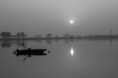 Silhouette boat in lake against sky