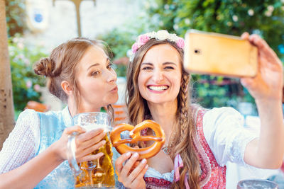 Portrait of smiling young woman holding smart phone outdoors