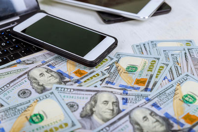 High angle view of technologies with paper currency on desk