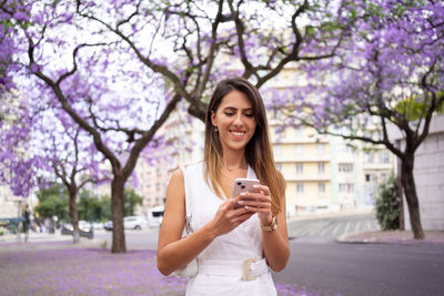 Portrait of young woman drinking water while standing in park