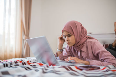 Young woman using digital tablet while sitting on table