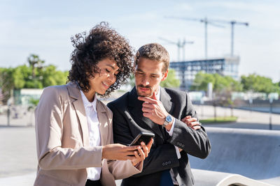 Portrait of smiling friends using mobile phone