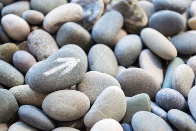 Abstract smooth round pebbles sea texture background with a white arrow pointer on the stone