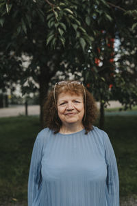 Portrait of smiling senior woman standing at park