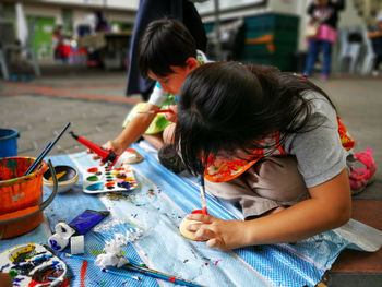 Siblings painting while sitting outdoors