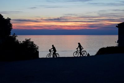 Two people riding bikes near sea
