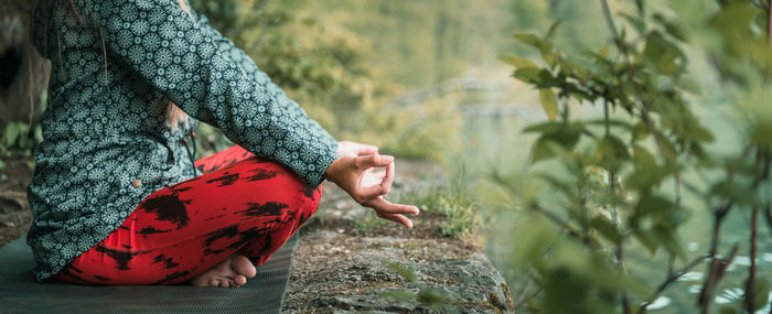 Low section of woman doing yoga on rock