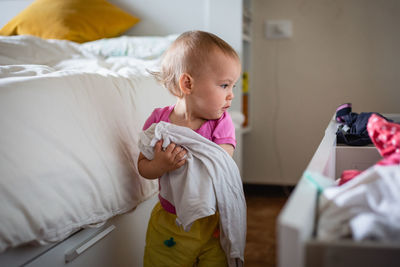 Busy baby playing with clothes in drawers, tidies up the bedroom