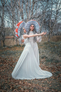 Woman with umbrella standing against trees