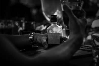 Close-up of hand holding glass bottle on table at restaurant