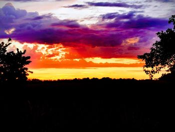 Scenic view of dramatic sky over silhouette trees during sunset