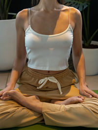 Midsection of woman doing yoga at home