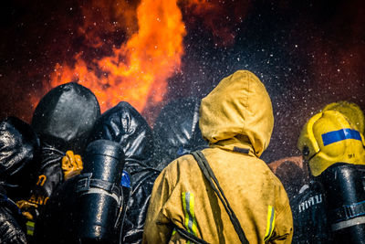 Rear view of firefighters spraying water on fire