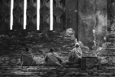 Rear view of monks sitting at buddhist temple