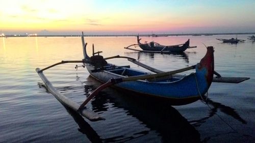 Boats moored in sea at sunset