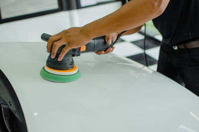 Midsection of man cleaning car at garage