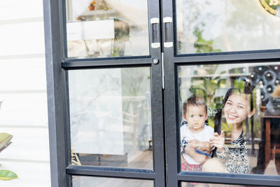 Portrait of mother and baby looking through window