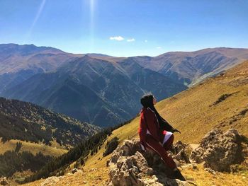 Man sitting on mountain looking at mountains
