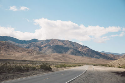 Scenic view of road by mountains against sky