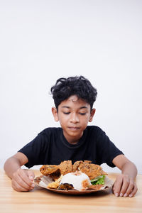 Portrait of young woman eating food against white background