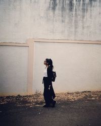 Side view of woman looking away against wall