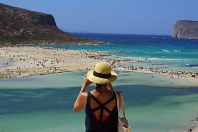 Rear view of woman overlooking calm blue sea