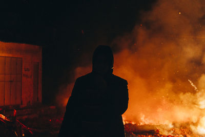 Silhouette man standing against fire at night