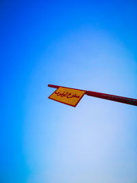 Low angle view of road sign against blue sky