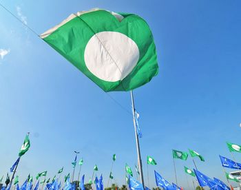 Low angle view of flags against clear blue sky