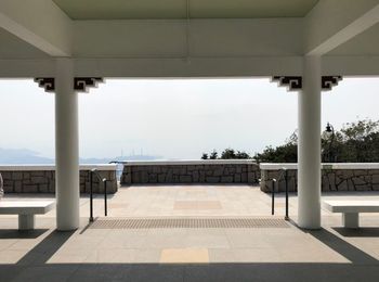 Empty benches against built structure and sea against clear sky