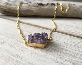 Close-up of amethyst with gold necklace on table
