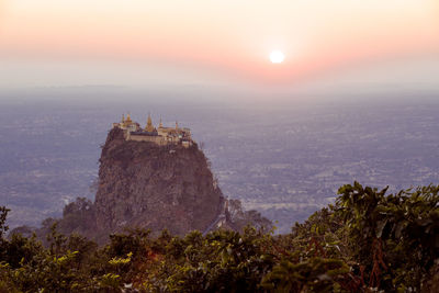 Temple on mountain peak against sky during sunrise