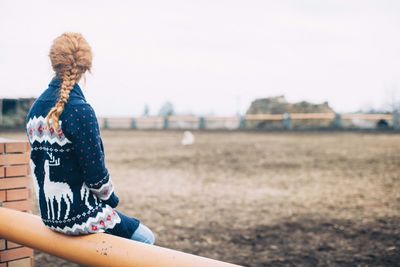 Rear view of caucasian girl sitting on railing
