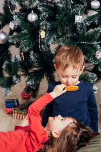 Happy cheerful children under the christmas tree. the girl shows the boy a christmas decoration