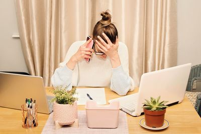 Stressed businesswoman working from her home office using laptop and smartphone