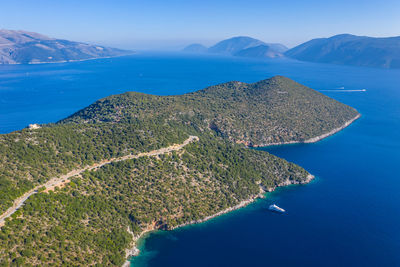 High angle view of sea and mountains against blue sky