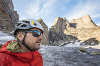 Portrait of climber wearing helmet and sunglasses below mountain summi