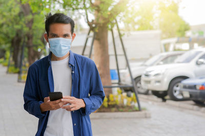 Man holding mobile phone while standing on street