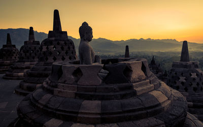 Ancient statue against sky during sunset